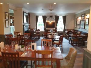 uma sala de jantar com mesas e cadeiras de madeira em The Evenlode Hotel em Witney
