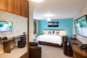 a hotel room with a bed and a desk and a tv at Abbeyfield Lodge in Stockton-on-Tees