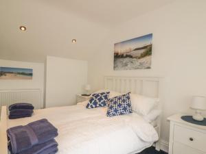 a bedroom with a white bed with blue pillows at Summer Breezes in Newquay