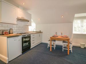 a kitchen with white cabinets and a wooden table at Summer Breezes in Newquay