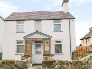 a white house with a wooden door at Ty Capel in Pwllheli