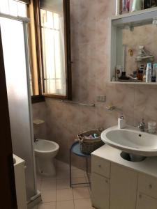 W łazience znajduje się umywalka, toaleta i lustro. w obiekcie Appartamento curato con giardino w mieście Marina Romea