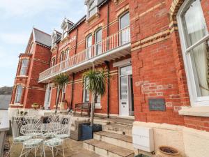 a red brick building with chairs and a porch at Beaulieu House in Llandudno