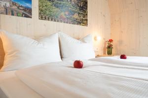 two red apples sitting on top of two white beds at Hotel Bergamo in Ludwigsburg