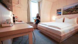 a woman in a hotel room with a bed at Hotel Bergamo in Ludwigsburg
