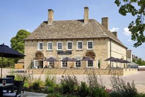 a large stone building with umbrellas in front of it at The Evenlode Hotel in Witney