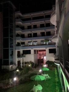 a building at night with green umbrellas in a yard at Hotel Satyam in Banepa