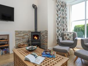 a living room with a fireplace and a table with books at Bryn Dale in Trearddur