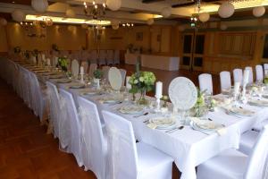 einen langen Tisch mit weißen Tischen und Stühlen in einem Zimmer in der Unterkunft Gasthof-Hotel Jaritz in Semriach