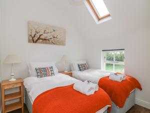 sypialnia z 2 łóżkami i pomarańczowymi kocami w obiekcie The Old White Cottage w mieście Shillelagh