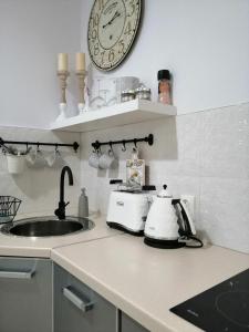 a kitchen counter with a sink and a clock on the wall at Apartament Rondo in Trzebinia