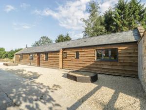 uma cabana de madeira com um banco à frente em The Milking Barn em Yeovil