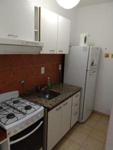 eine Küche mit einem Herd, einer Spüle und einem Kühlschrank in der Unterkunft Departamentos Carbó in Paraná