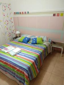 uma cama com um cobertor colorido e almofadas em Departamentos Carbó em Paraná