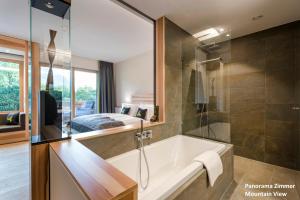 a bathroom with a bath tub and a bedroom at Klosterhof – Alpine Hideaway & Spa in Bad Reichenhall