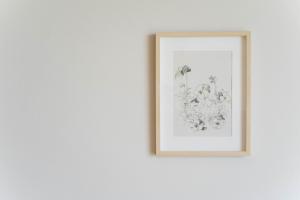 a framed picture of flowers on a white wall at Sandbox Beachfront Villa 3 in Ban Krathing Lai