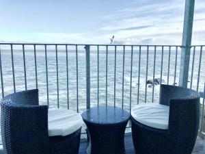 a balcony with two chairs and a table and the ocean at SeaSound in Ilfracombe