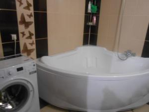 a bathroom with a white tub next to a washing machine at Цитадель к15 in Omsk
