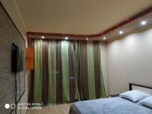 a bedroom with a bed and a green curtain at Цитадель к15 in Omsk
