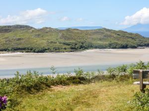 a bench sitting on a hill overlooking a beach at 2 Tougal in Mallaig