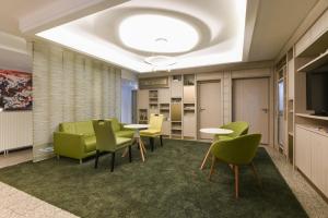 a waiting room with green chairs and tables and a television at HOTEL Am Spichernplatz in Düsseldorf