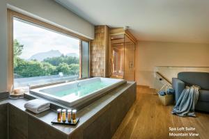a bathroom with a large tub with a large window at Klosterhof – Alpine Hideaway & Spa in Bad Reichenhall