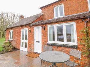 a brick house with a table and chairs on a patio at Wigrams Canalside Cottage in Southam