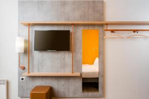 Habitación con TV, cama y espejo. en ibis budget Strasbourg La Vigie en Ostwald