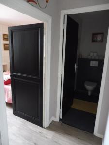 a black door leading to a bathroom with a toilet at La Lézardière in La Rochefoucauld