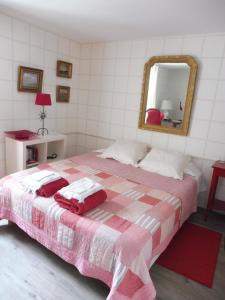a bedroom with a pink and white bed with a mirror at La Lézardière in La Rochefoucauld