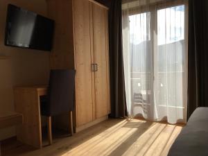 a bedroom with a bed and a television and a window at Platzerhof in Monguelfo