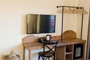 a television on a wall with a wooden desk with a chair at 19.40 Luxury Guesthouse in Kalpákion