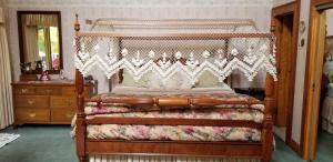 a bedroom with a canopy bed and a dresser at Whisperin' Pines Chalet in Cooperstown