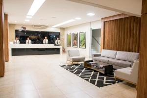 a lobby with a couch and chairs and a bar at Hotel Vale Verde in Campo Grande