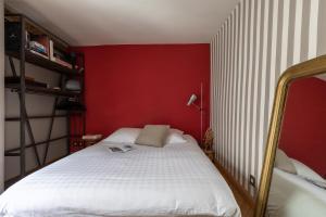 a bedroom with a white bed with a red wall at Appartement Luxe Montorgueil bail mobilité Opera Louvre in Paris