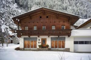 Casa de madera grande con nieve en el suelo en Chalet Walchenhof en Mayrhofen