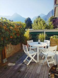 Una mesa blanca y sillas en una terraza de madera. en Camp de base, en Le Bourg-dʼOisans