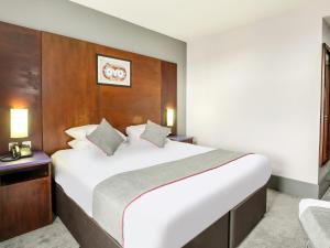 a bedroom with a large white bed with a wooden headboard at OYO Flagship Sheffield City Centre in Sheffield