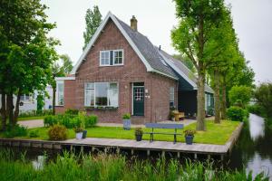 una casa con una panchina di fronte a un fiume di Idyllic Farmhouse a Landsmeer