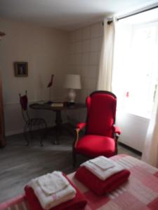 a bedroom with a red chair and a desk and a bed at La Lézardière in La Rochefoucauld