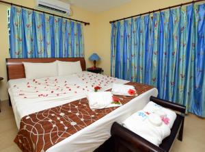 a bedroom with a large bed with blue curtains at Le Relax Self Catering Apartment in La Digue