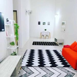 a living room with an orange couch and a checkered floor at Nur Zahra Sungkai Homestay in Sungkai