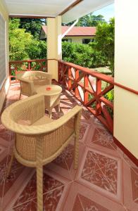 a patio with wicker chairs and tables on a balcony at Le Relax Self Catering Apartment in La Digue