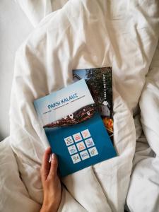 a person laying on a bed with two books at Erzsébet Nagy Szálloda in Paks