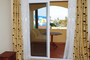 a sliding glass door with curtains in a room with a table at HOTEL MENABE in Morondava