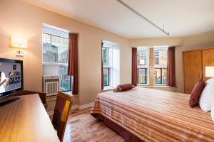 Schlafzimmer mit einem Bett, einem TV und Fenstern in der Unterkunft Hotel Abri du Voyageur in Montreal