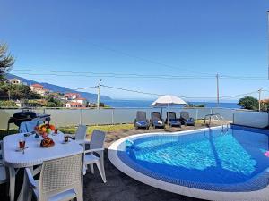 a swimming pool with a table and chairs next to it at Villa North Sea by LovelyStay in Ponta Delgada