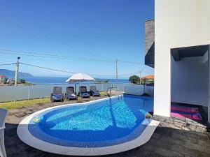 a swimming pool with two chairs and an umbrella at Villa North Sea by LovelyStay in Ponta Delgada