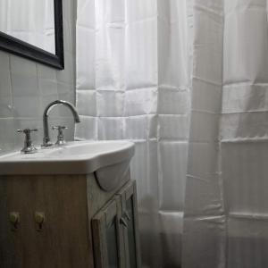 uma casa de banho com um lavatório e uma cortina de chuveiro branca em SUH Apartment em Buenos Aires