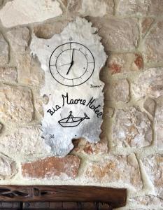 a clock on the side of a stone wall at Hotel Bia Maore in Baunei